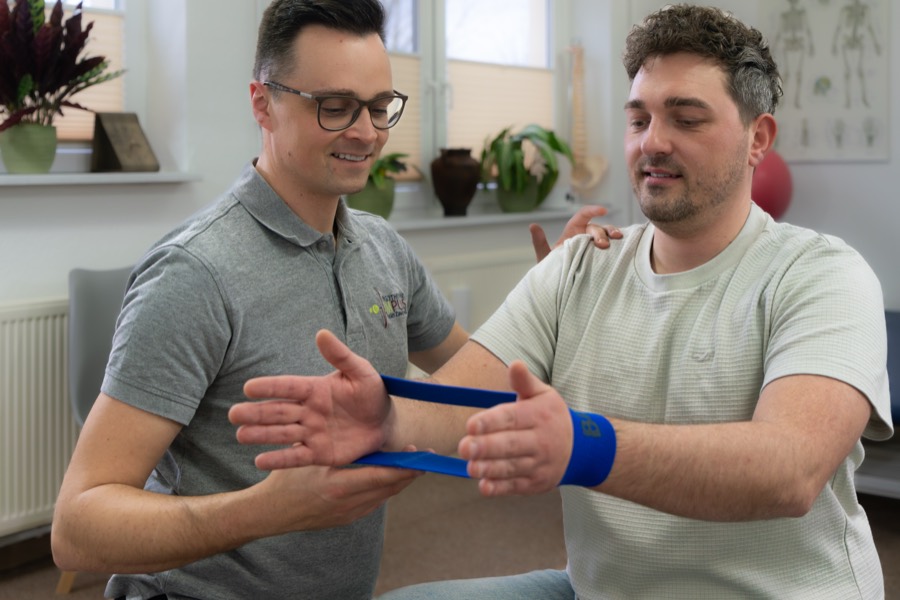Therapeut übt mit einem Patienten die Beweglichkeit des Arms